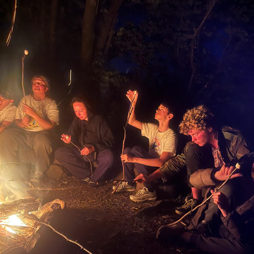 Group of friends around a camp fire roasting marshmallows