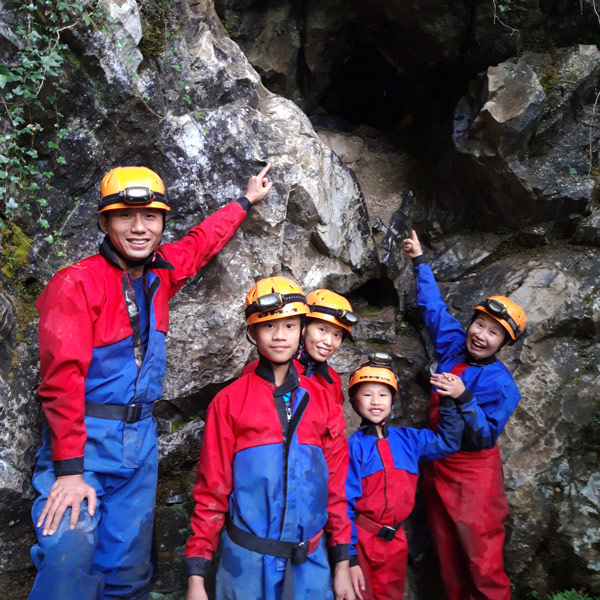 Family pointing at the Llygad Llwchwr cave entrance nervously as it's high up and small.